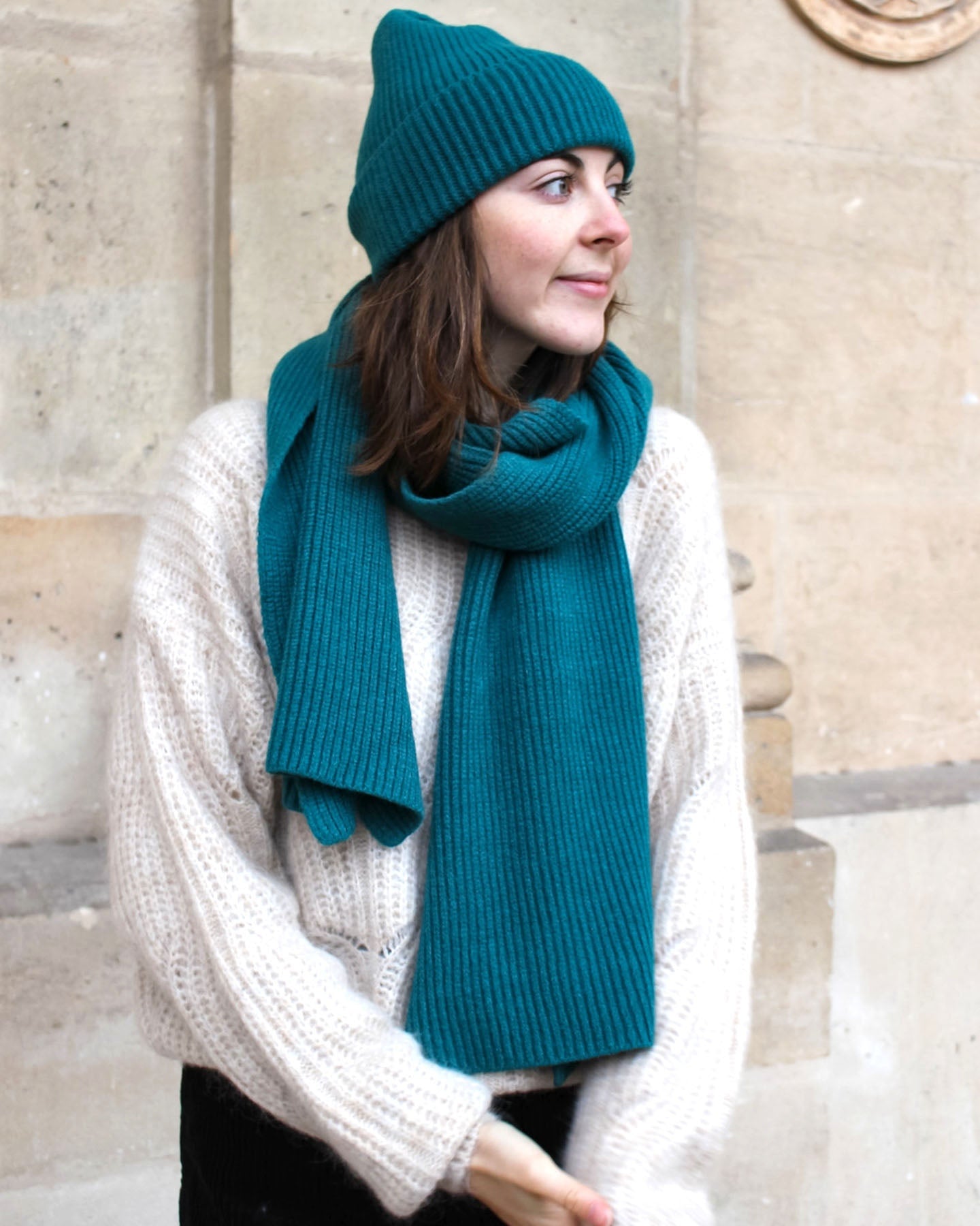 a woman in a green coat and hat is walking down the street 